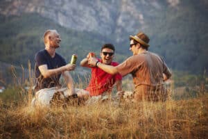 Three friends enjoying a can of beer outdoors